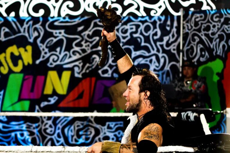 Wrestler celebrating in front of the JCW Lunacy banner