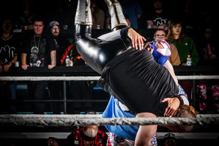 Wrestler hoisting an opponent near the ropes