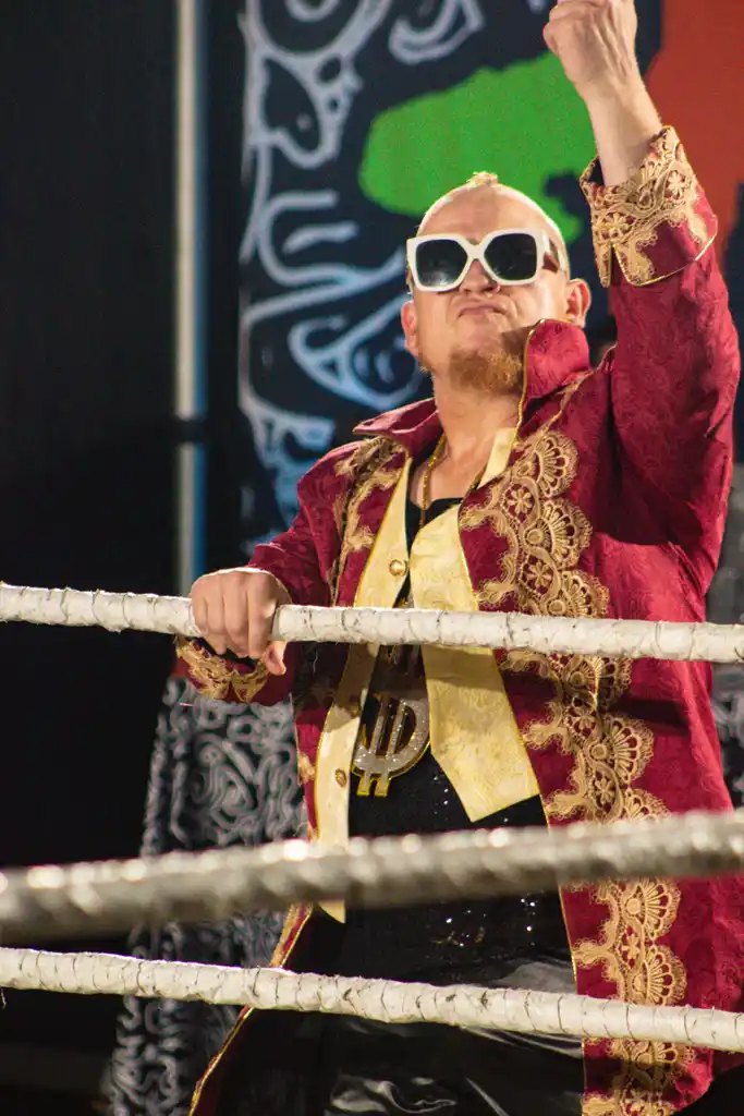 Wrestler in a red and gold robe on the ropes